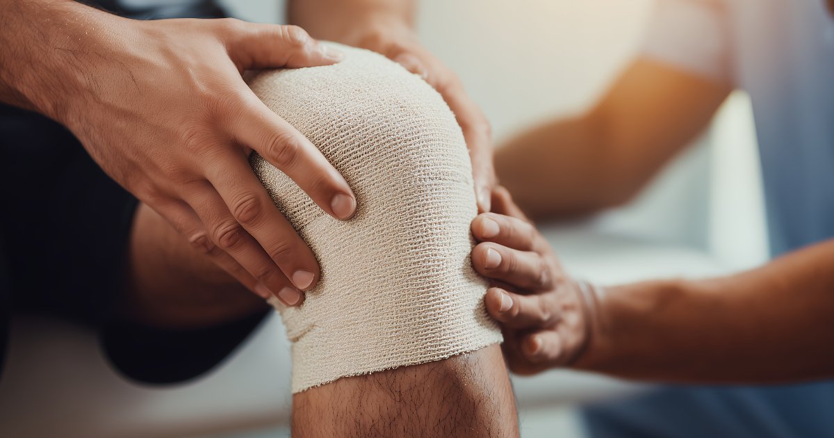 Clinician examining a patient's bandaged knee