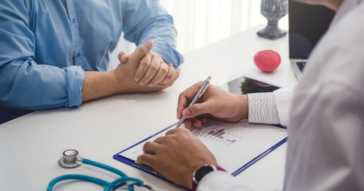 Doctor taking notes during a consultation with a male patient